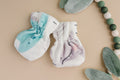 Polyester baby mittens with dinosaur characters next to fake leaves and green and white beads